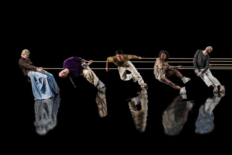 5 People hang from a rope on standing on a mirrored stage