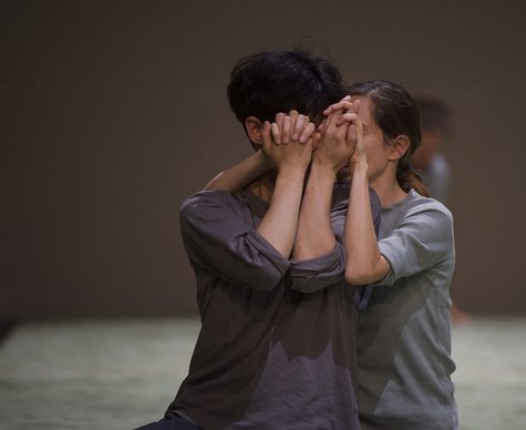 Fotografie zweier Personen, die ihre Gesichter mit ihren Händen bedecken. Die Hände sind ineinandergeschlungen.